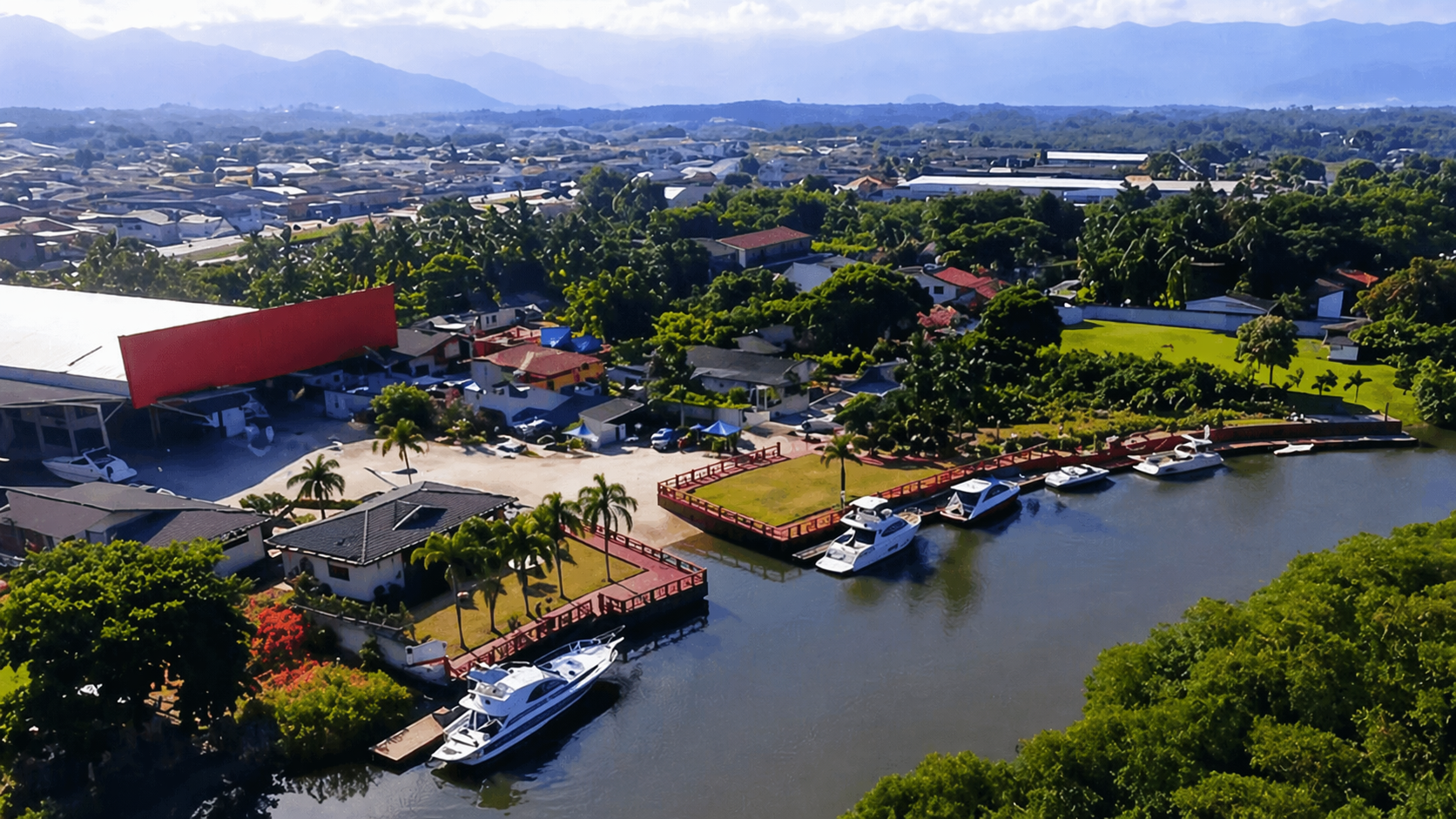 Vista aérea da Marina Imperial em Caraguatatuba, com deck à beira do Rio Juqueriquerê, iates atracados e a Serra do Mar ao fundo